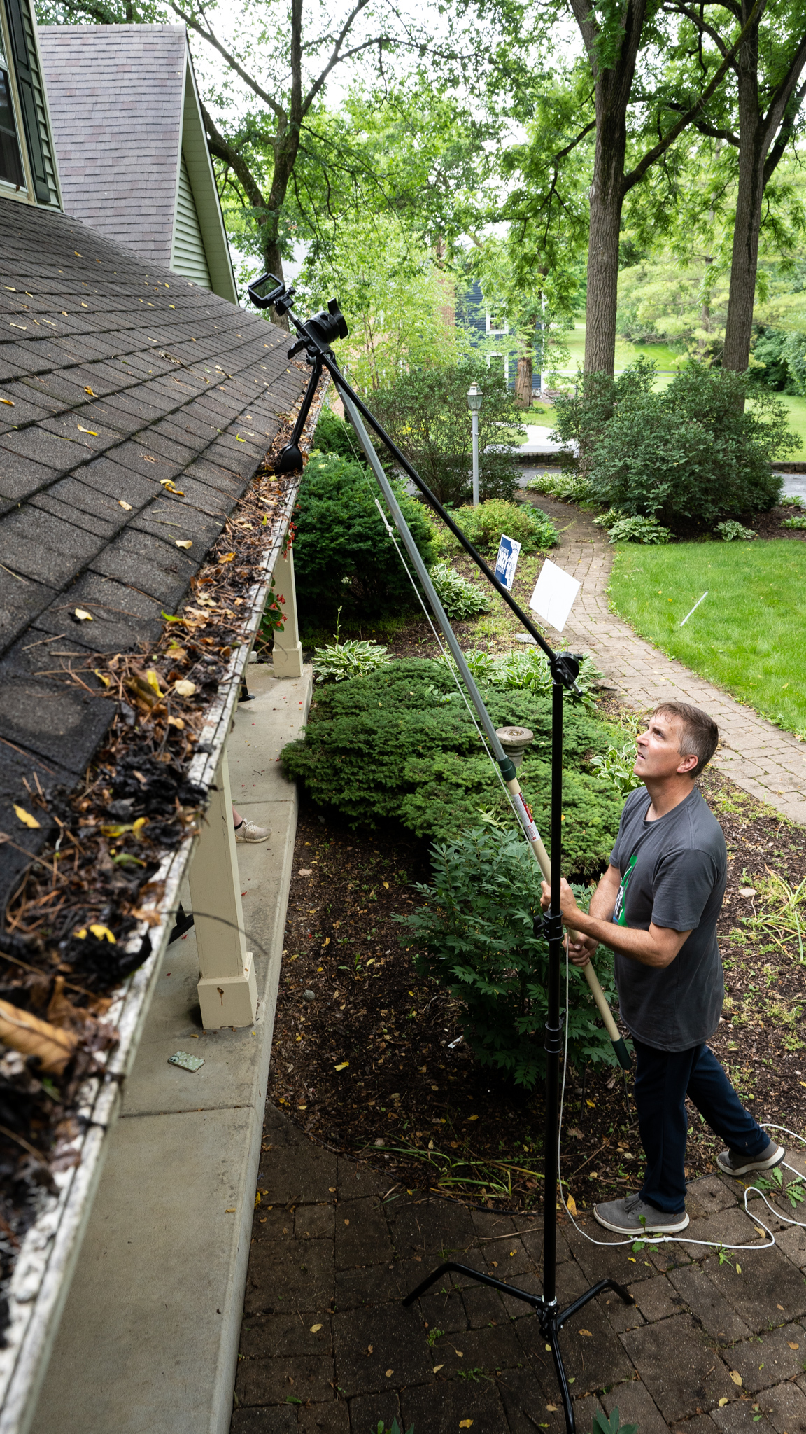 Man cleaning gutters from the ground with Gutter Sense